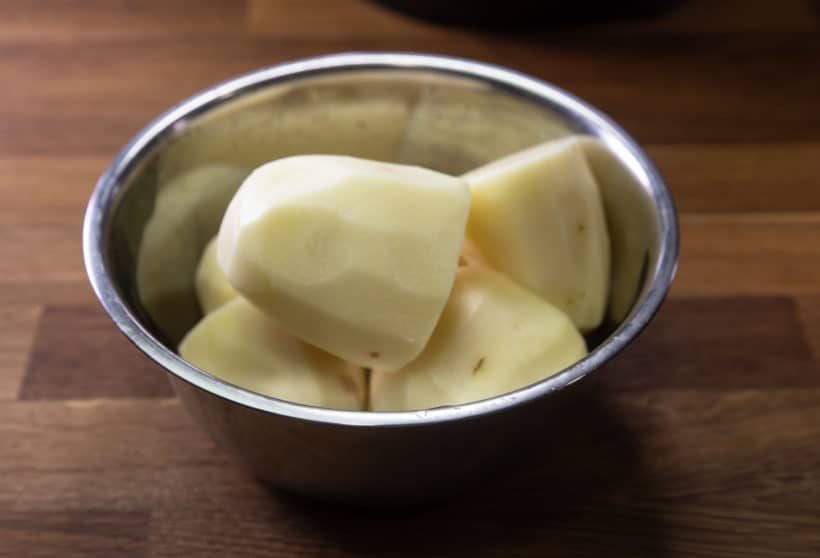 layer stainless steel bowl of halved potatoes on top of short ribs