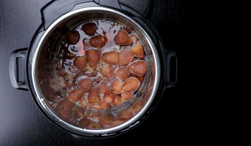 How to make Instant Pot Strawberry Compote Recipe (Pressure Cooker Strawberry Compote): stir and break strawberries with a wooden spoon.