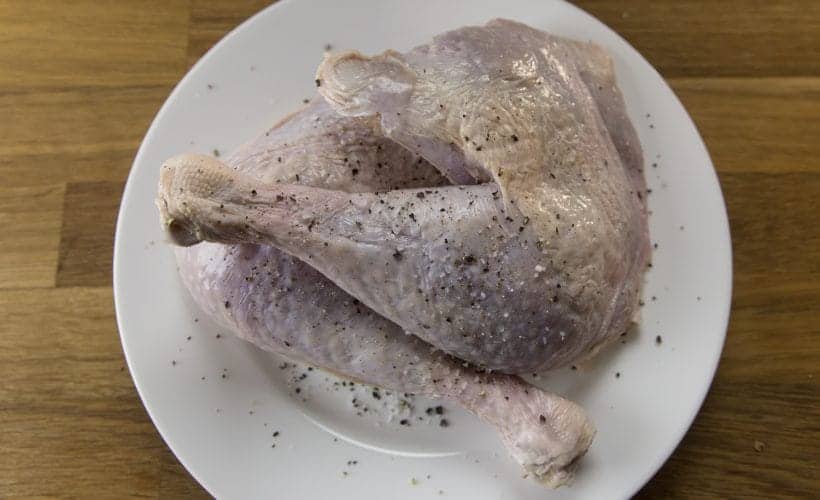 preparing turkey quarters with kosher salt and ground black pepper