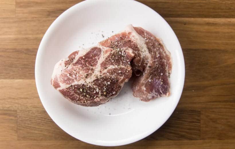 seasoning pork shoulder with kosher salt and ground black pepper